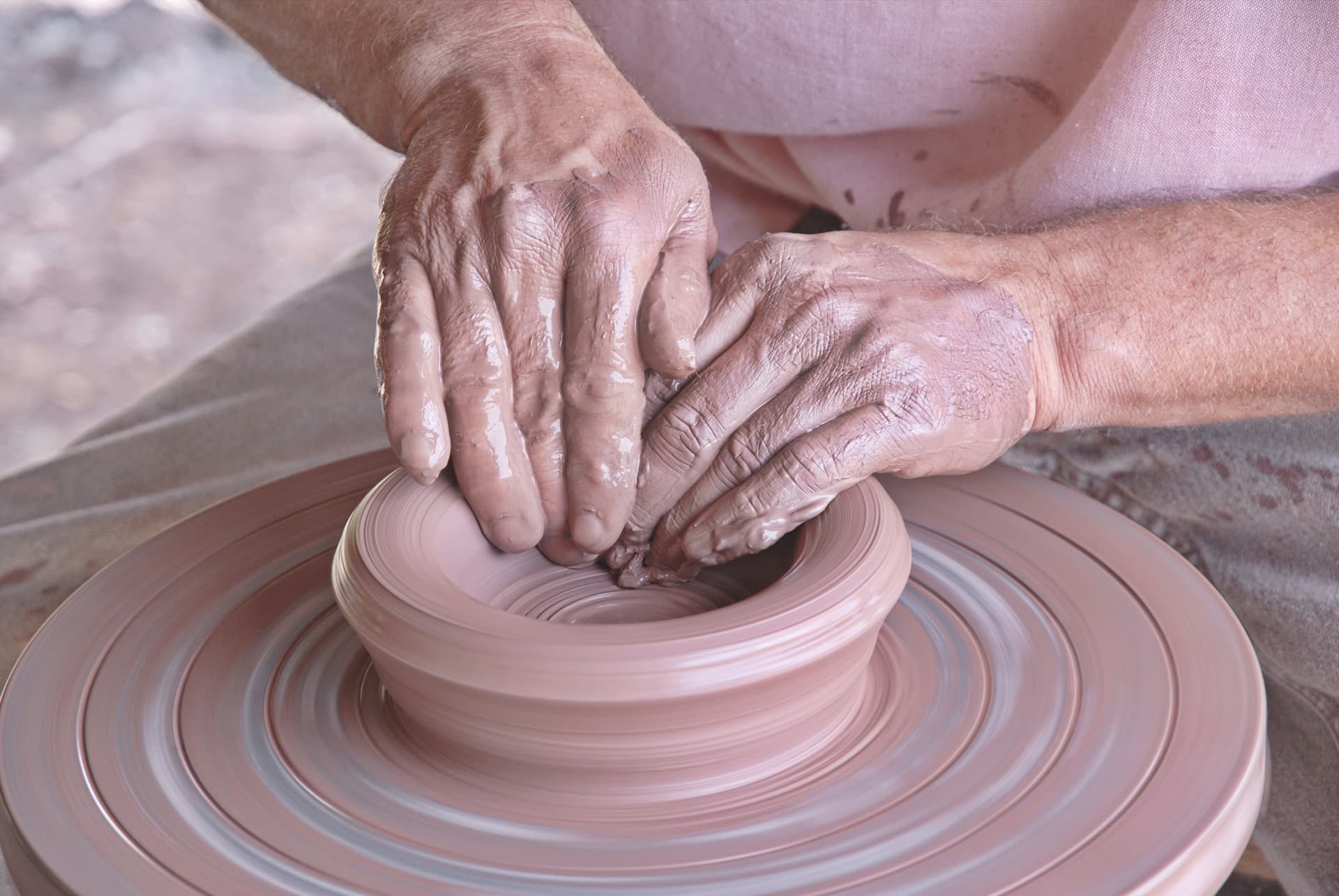 a woman is making a vase out of clay